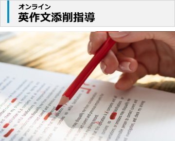 英文が書かれた紙の上。赤ペンで添削している